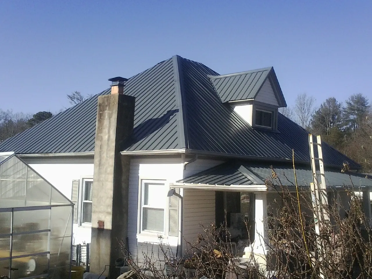 Dark blue standing seam metal roof on a white farmhouse with dormer — Slate & Tile Roof Repair by Roofing Brothers in Ellensburg