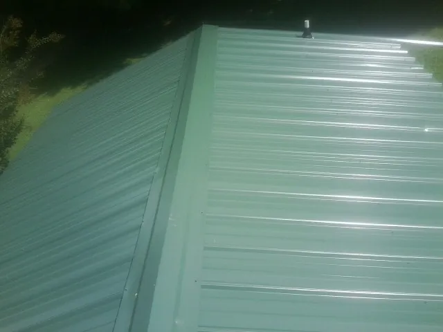 New green metal panels meeting at the ridge of a roof — Flat Roof Repair work by our crew in Ellensburg