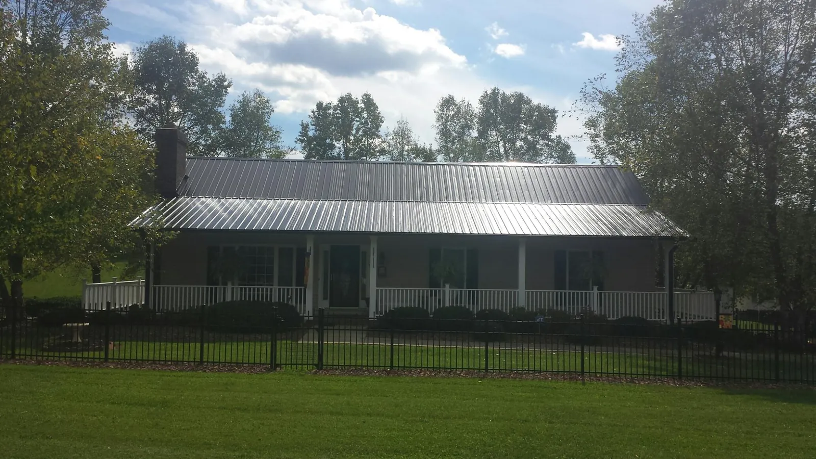 Gray metal roof on a brick ranch with a full width front porch — Gutter Guard Installation work by our crew in Ellensburg