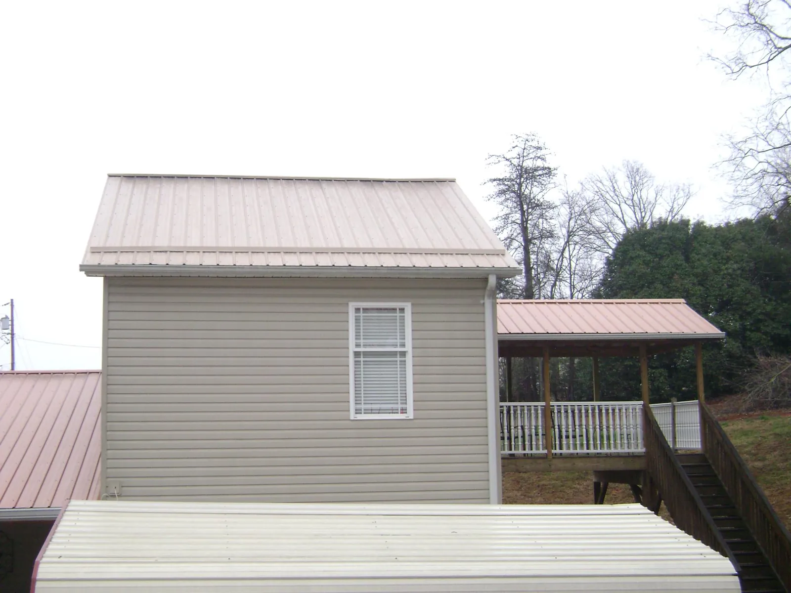 Tan metal roofs on a two story addition and attached porch, from a Roof Replacement job in Ellensburg