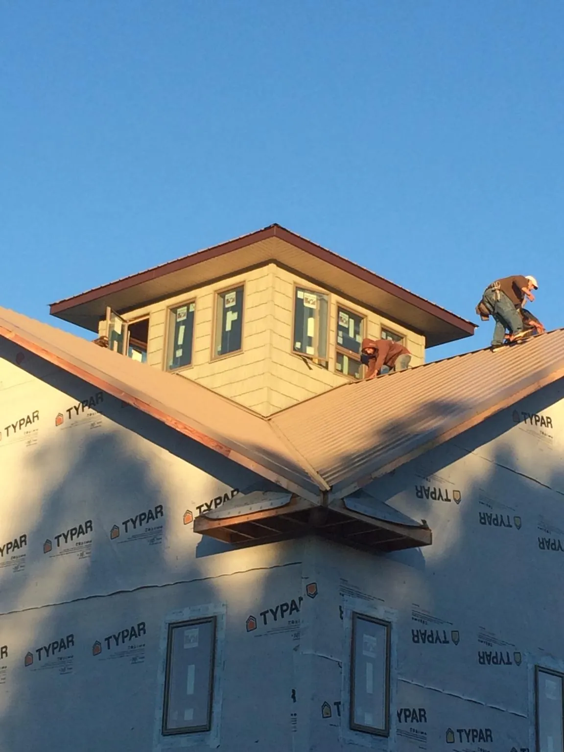 Roofers working around a rooftop cupola on a new metal roof at sunset — Roof Waterproofing in Ellensburg by Roofing Brothers